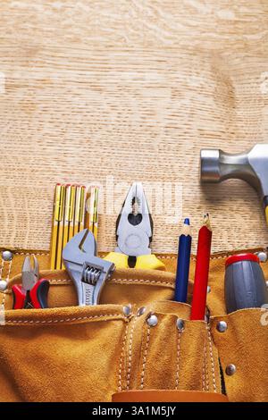 Pinces pinces pinces pince-étau marteau crayon dans la ceinture à outils sur planche de bois Banque D'Images