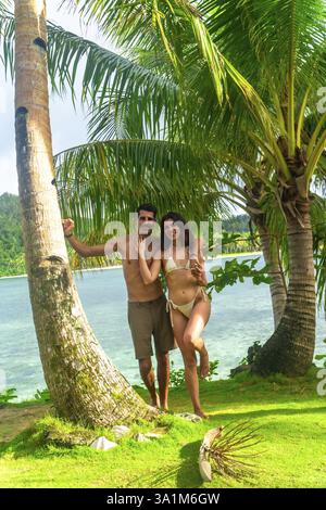 Couple se relaxant sous les palmiers sur la belle île de kawhagan à Siargao, philippines, profitant des eaux turquoise et de la verdure luxuriante Banque D'Images