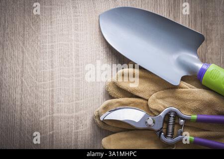 Sécateur cisailles à main bêche et gants de sécurité en cuir sur le concept de jardinage en planche de bois Banque D'Images