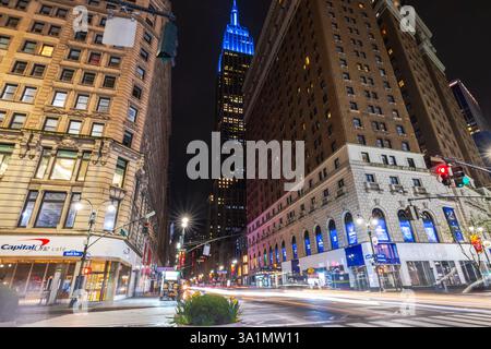 Traînées légères de voitures en mouvement à l'intersection de la 34e rue et de la Sixième avenue avec l'Empire State Building la nuit New York. ÉTATS-UNIS. Banque D'Images
