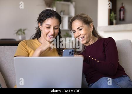 Femmes latines jeunes et âgées utilisant un ordinateur portable et un smartphone Banque D'Images