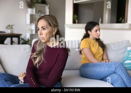 Mère mature assise séparément sur le canapé avec sa fille adulte Banque D'Images