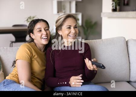 Heureuse mère et jeune fille adulte regardant l'émission de télévision préférée Banque D'Images