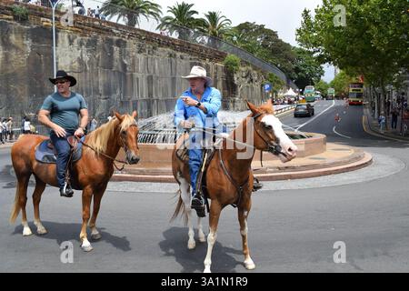 Scène unique de deux cow-boys chevauchant un cheval dans les rues urbaines de Sydney, mêlant charme occidental et dynamique paysage urbain australien. Banque D'Images