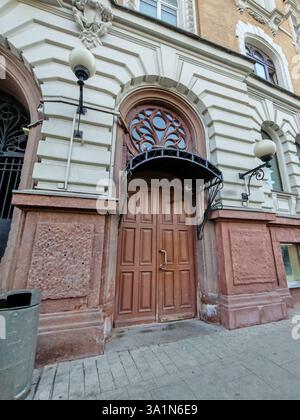 Une porte en bois vieilli entourée de pierres sculptées et surmontée d'un auvent en fer forgé. L'image véhicule des thèmes de design intemporel et urbain Banque D'Images