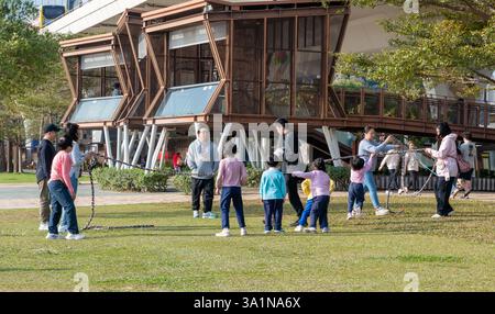 Hong Kong. Chine- 02.15.2025. Les parents et les enfants profitent d'une chaude journée ensoleillée avec du plaisir et des jeux sur la promenade de Kwun Tong. Banque D'Images