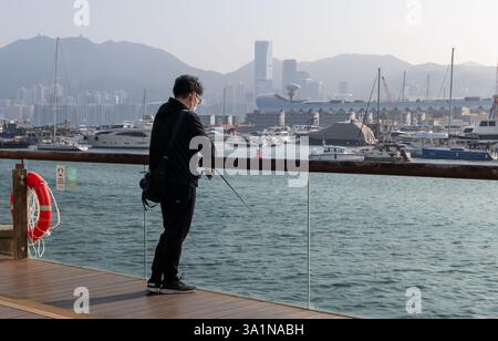 Hong Kong. Chine- 02.15.2025. Un jeune homme qui pêche un peu sur la promenade de Kwun Tong à East Kowloon. Banque D'Images