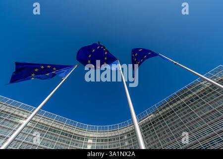 Trois drapeaux européens, symboles de l'Union européenne (UE), flottant sur fond de ciel bleu et le siège de la Commission européenne Banque D'Images