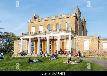 Les gens apprécient le soleil au début du printemps devant Clissold House, un bâtiment classé Grade II à Clissold Park, Hackney, Londres, Royaume-Uni Banque D'Images