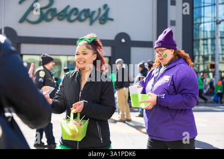 Scranton, PA - 8 mars 2025 : pendant la défilé de Patrick, les gens marchent et distribuent des bonbons et des souvenirs. Banque D'Images