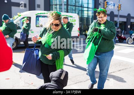 Scranton, PA - 8 mars 2025 : pendant la défilé de Patrick, les gens marchent et distribuent des bonbons et des souvenirs. Banque D'Images