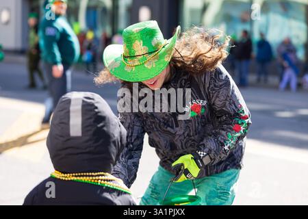 Scranton, PA - 8 mars 2025 : pendant la défilé de Patrick, les gens marchent et distribuent des bonbons et des souvenirs. Banque D'Images