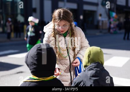 Scranton, PA - 8 mars 2025 : pendant la défilé de Patrick, les gens marchent et distribuent des bonbons et des souvenirs. Banque D'Images