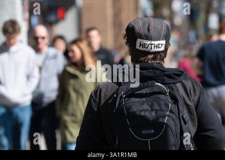 Ann Arbor, Michigan, États-Unis. 9 mars 2025. Une personne se promène dans le centre-ville d'Ann Arbor avec les pronoms, il/elle, patché sur le dos de leur chapeau de style gatsby le 9 mars 2025. (Crédit image : © Mark Bialek/ZUMA Press Wire) USAGE ÉDITORIAL SEULEMENT! Non destiné à UN USAGE commercial ! Banque D'Images