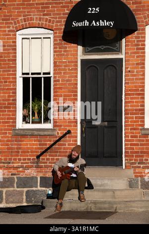 Ann Arbor, Michigan, États-Unis. 9 mars 2025. Un homme joue une guitare à cordes en nylon sur Ashley Street dans le centre-ville d'Ann Arbor, Michigan le 9 mars 2025. (Crédit image : © Mark Bialek/ZUMA Press Wire) USAGE ÉDITORIAL SEULEMENT! Non destiné à UN USAGE commercial ! Banque D'Images