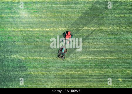 Vue aérienne d'un champ avec des tracteurs et des charrues prêts à labourer le terrain. Culture printanière de la terre. Banque D'Images