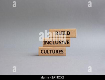 Symbole construire des cultures inclusives. Les blocs de bois avec des mots construisent des cultures inclusives. Beau fond gris. Entreprise et construire des cultures inclusives. Banque D'Images
