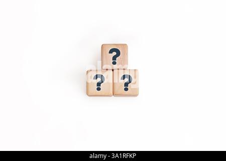 Trois blocs de bois avec des points d'interrogation sombres empilés en forme de pyramide sur fond blanc. Symboliser des concepts comme la résolution de problèmes Banque D'Images