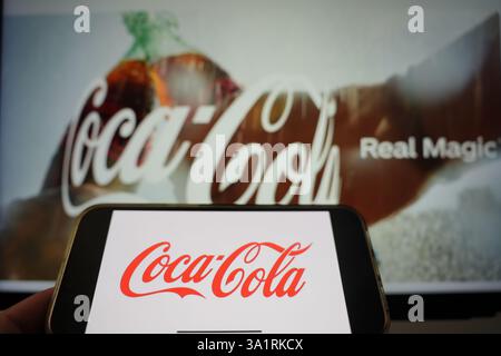 Roosendaal, pays-Bas - 10 mars 2025 : un téléphone portable affichant le logo de Coca-Cola, avec le site Web de l'entreprise et le produit en arrière-plan. Banque D'Images