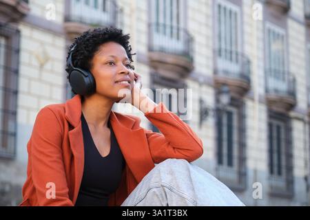 Jeune femme appréciant la musique avec des écouteurs dans la ville Banque D'Images