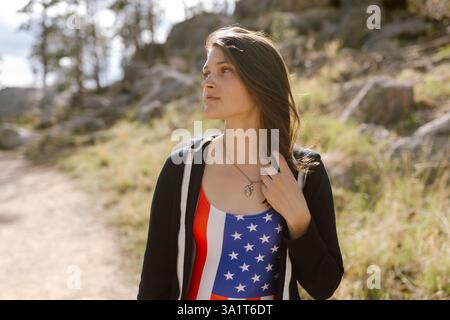 Femme dans un maillot de bain drapeau américain se tient à la lumière du soleil dans Black Hills. Banque D'Images