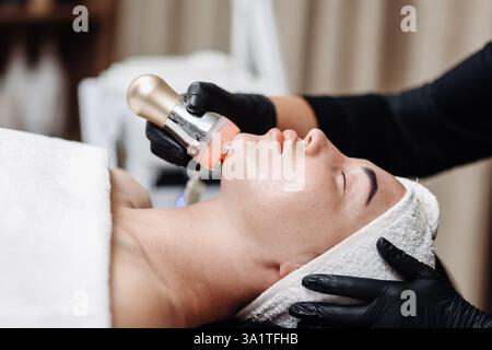 Gros plan d'une femme recevant un lifting facial par cavitation échographique. L'image capture le traitement anti-âge avancé Banque D'Images
