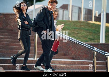 Descendre les escaliers. Trois jeunes étudiants sont à l'extérieur de l'université à l'extérieur. Banque D'Images