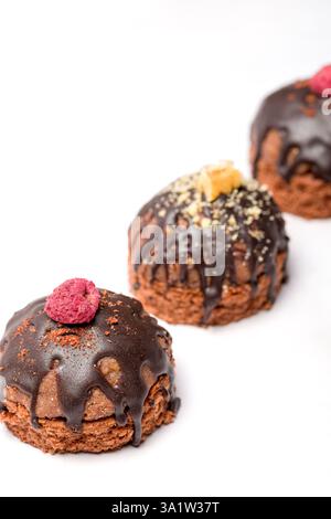 Gâteaux ronds au chocolat. Décoré de framboises confites. Arrière-plan clair. Banque D'Images