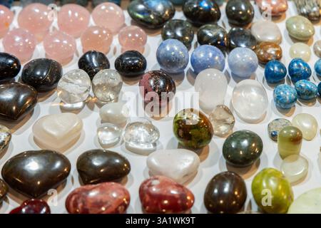 Diverses pierres précieuses polies aux nuances et motifs variés, comprenant des pierres translucides claires et des minéraux opaques dans une présentation décorative. Banque D'Images