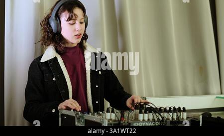 Une fille interagit avec une table d'harmonie, son sourire reflétant son enthousiasme pour la musique ou le mixage sonore. Cette photo évoque des thèmes de créativité, de concentration et Banque D'Images