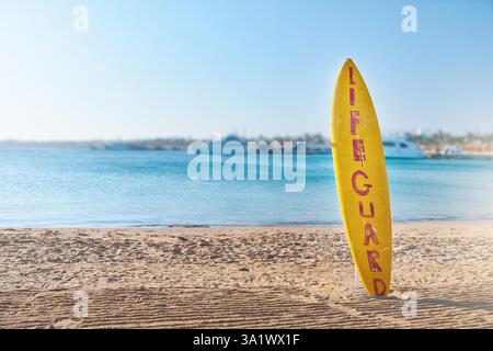 Cercle de bouée de sauvetage et planche de surf pour sauvetage. Vue panoramique de bouée de sauvetage rouge et blanche sur le poteau sur la plage de bord de mer. Paysage de paysage de la rive de l'océan de mer sur sunn Banque D'Images