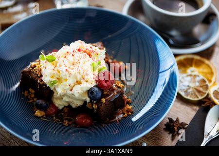 Gâteau Brownie au caramel salé. Mousse anglaise, sauce framboise, noix pralinée et baies fraîches. Délicieux dessert sucré en gros plan servi pour le déjeuner Banque D'Images