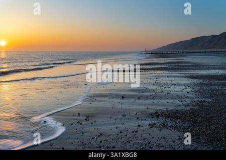 Lever de soleil sur la plage à Mundesley, Norfolk, Royaume-Uni, avec le soleil se levant au-dessus de l'horizon Banque D'Images