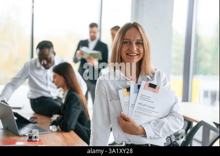Portrait de femme blonde heureuse. Groupe d'employés de bureau sont ensemble à l'intérieur. Banque D'Images