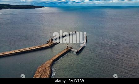Vue aérienne de deux jetées avec des phares s'étendant dans l'océan sous un ciel partiellement nuageux à Whitby, Royaume-Uni. Banque D'Images