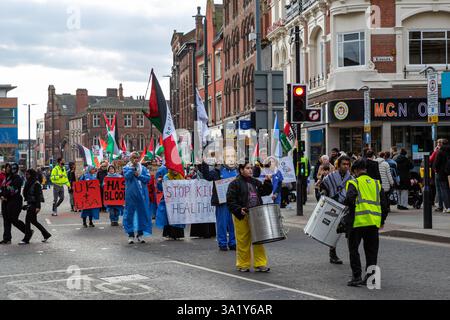 Une vue au niveau de la rue d'une marche de protestation dans une rue de la ville avec des manifestants tenant des pancartes, des drapeaux et jouant de la batterie. Banque D'Images