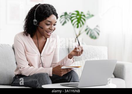 Joyeux Black Femme en ligne tuteur expliquant le sujet à l'étudiant via Appel vidéo Banque D'Images