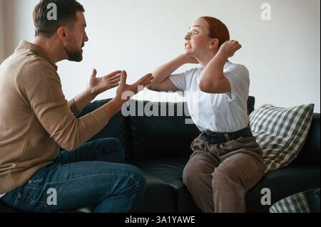 Vue latérale du couple qui se disputent. Assis sur le canapé. Banque D'Images