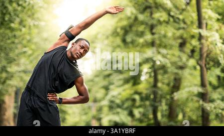 Homme noir qui s'étire le corps, fait du sport à l'extérieur Banque D'Images