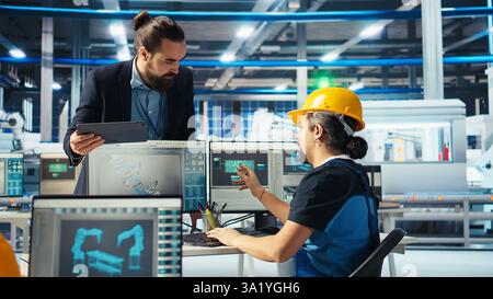 L'ingénieur d'usine photovoltaïque planifie le travail sur le sol de l'installation dans un logiciel de CAO, montrant le chef d'équipe. Technicien d'usine de fabrication de panneaux solaires concevant des lignes d'assemblage, informant le gestionnaire, caméra A. Banque D'Images