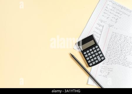 Copybook avec formules mathématiques manuscrites, crayon et calculatrice sur fond jaune Banque D'Images
