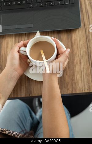 Un moment moderne et esthétique où les mains enveloppent délicatement une tasse élégante de chocolat chaud crémeux, embrassant la chaleur et la saveur indulgente dans un Banque D'Images