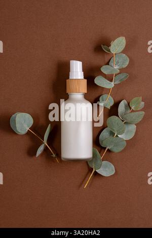Crème pour le visage ou le corps en flacon pompé en verre blanc givré avec des extraits naturels d'eucalyptus et des huiles. Cosmétiques pour le soin de la peau. Traitement à base de plantes. Banque D'Images