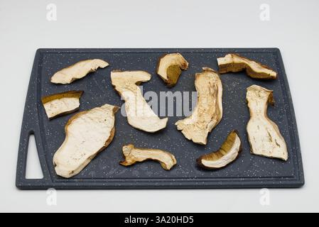Diverses tranches de champignons porcini séchés disposées sur une planche à découper. Banque D'Images