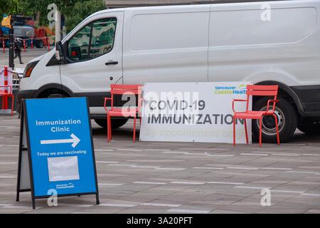 Vancouver, Canada - le 9 août 2021 : installation d'une clinique mobile d'immunisation COVID-19 à Vancouver avec signalisation directionnelle, chaises rouges et une camionnette blanche Banque D'Images