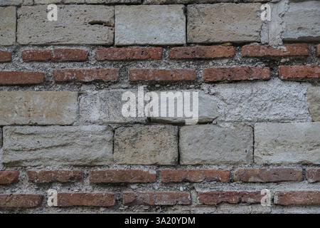 Mur construit à partir d'un mélange de briques rouges et de pierres grises met en valeur les techniques de construction traditionnelles en Albanie, mettant l'accent sur la durabilité et le design. Banque D'Images
