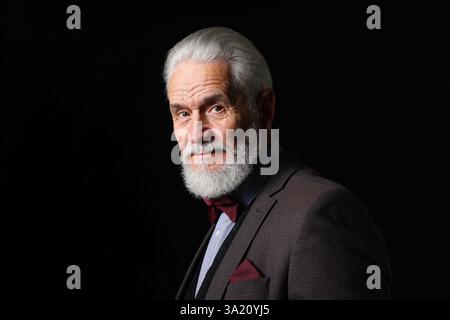 Portrait d'homme senior sérieux avec barbe argentée sur fond noir Banque D'Images