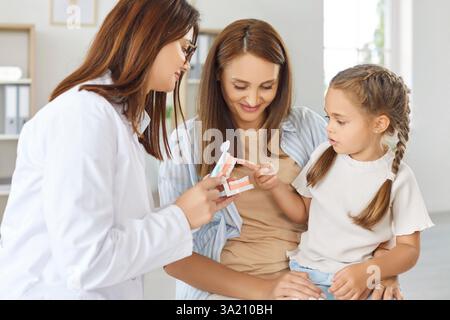 Dentiste ou infirmière montrant aux parents et à l'enfant comment brosser les dents Banque D'Images