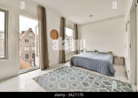Une chambre moderne magnifiquement conçue avec une grande fenêtre, un décor de bon goût et une atmosphère chaleureuse, parfaite pour la détente et le confort. Banque D'Images