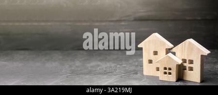 Maisons miniatures en bois sur fond noir. Logement abordable. Recherche achat meilleure option appartement et immobilier, loyer. Espace de copie, bannière Banque D'Images
